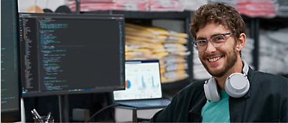 Uma imagem de um homem com fones de ouvido na frente de uma tela de computador