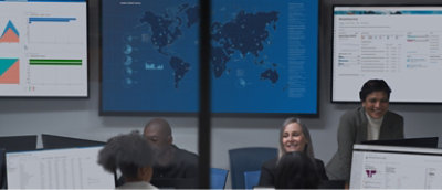 A group of people sitting in front of monitors in a conference room