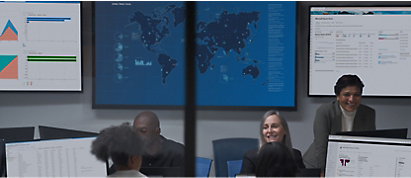 En gruppe personer, der sidder foran skærme i et mødelokale