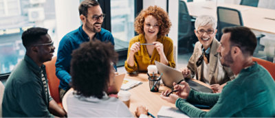 Eine vielfältige Gruppe von sechs Experten sitzt um einen Tisch in einem modernen Büro und führt ein gemeinsames Gespräch