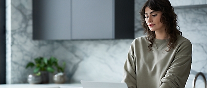 Uma mulher usando um laptop em uma cozinha.