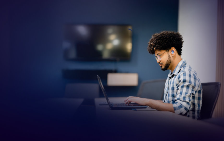 Man wearing a hearing aid working on laptop in an office.