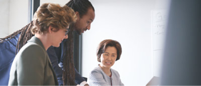 A group of business people looking at a laptop in an office.