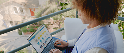 En kvinna använder en bärbar dator på en balkong.