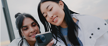Två kvinnor tar en selfie med sina mobiltelefoner.