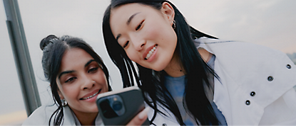 Zwei Frauen machen ein Selfie mit ihren Handys.