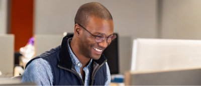 A man is smiling while working on a computer