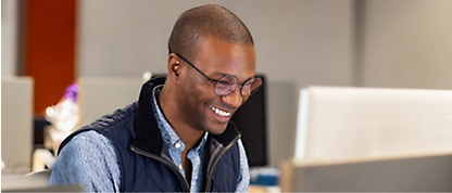 Um homem sorri enquanto trabalha num computador