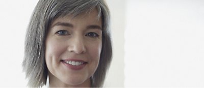 Femme aux cheveux gris souriant devant un arrière-plan blanc