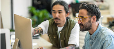 Deux hommes travaillant ensemble sur un ordinateur dans un environnement de bureau.