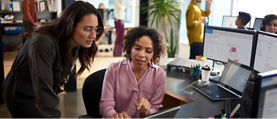 Duas mulheres trabalhando em um laptop em um escritório.