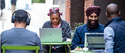Um grupo de pessoas sentadas em uma mesa usando laptops.