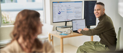 A man and woman talking to each other from their respective seats in an office.