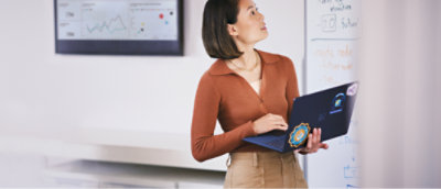 一位女士在白板前拿着笔记本电脑。
