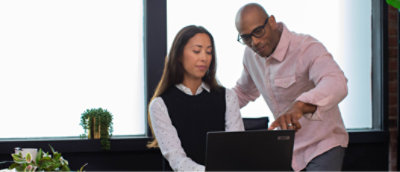 一位男士和一位女士正在办公室使用笔记本电脑工作。