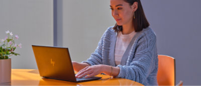 一位女士正坐在桌前使用笔记本电脑。