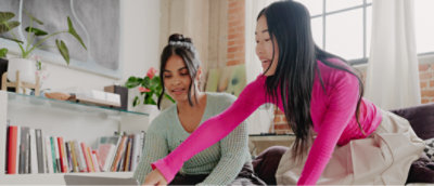 两位女士在客厅使用笔记本电脑工作。