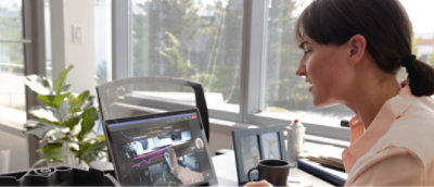 一位女士在窗前使用笔记本电脑工作。