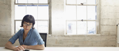 一位女士坐在放着手机的办公桌前。