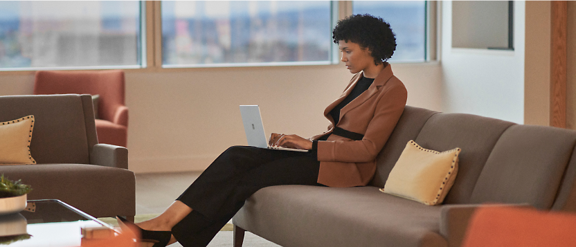 一位專業人士在現代化辦公室的休息區使用膝上型電腦。