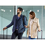 机场中一位男士和一位女士拖着行李。
