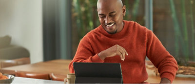 A man is sitting at a table with a laptop.