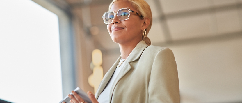 A business woman wearing glasses and holding a cell phone.