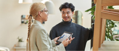 A man and woman looking at a tablet in a living room.