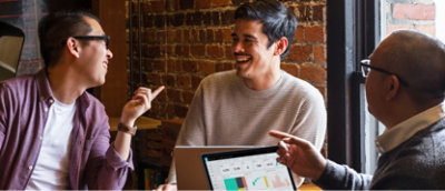 A group of people sitting around a table with laptops.