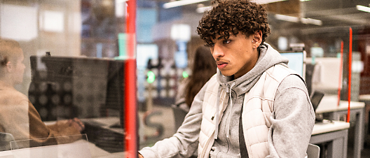 Young man with curly hair working at a computer in an office environment.