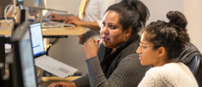 A person sitting at a desk with other people using computers