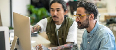 A group of men sitting and working on laptop