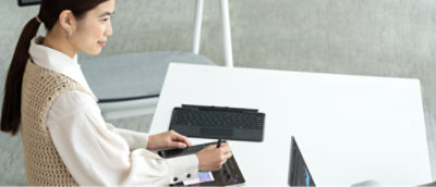 Een vrouw gebruikt een tablet terwijl ze naar een monitor kijkt