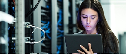 En kvinne som bruker et nettbrett på et serverrom.