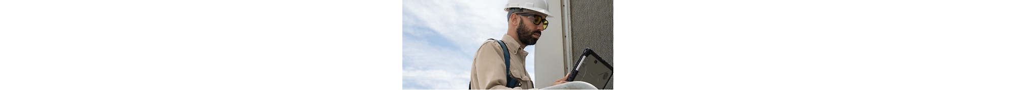 A man in a hard hat is using a laptop.