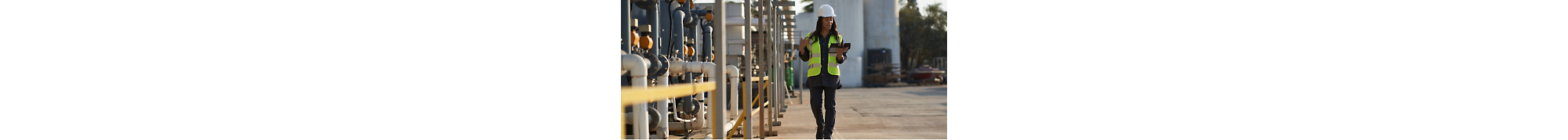 A woman in a hard hat is holding a tablet in her hand.