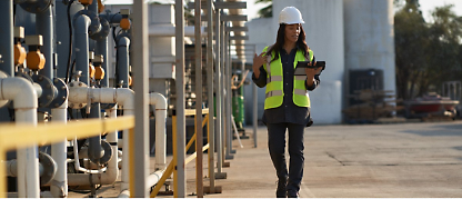 A woman in a hard hat is holding a tablet in her hand.