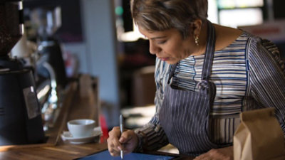 Eine Arbeitskraft in einem Café, die Stift und Tablet verwendet