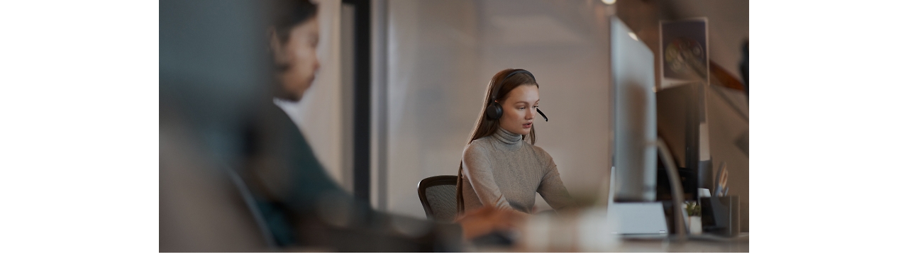 Una mujer está trabajando en un escritorio con unos auriculares.