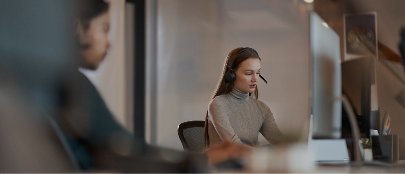 A woman wearing a headset is working at a desk.
