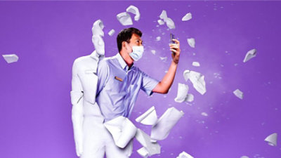 Eine Person mit einer Maske, die aus einer gegossenen Form ausbricht und ein Mobiltelefon benutzt