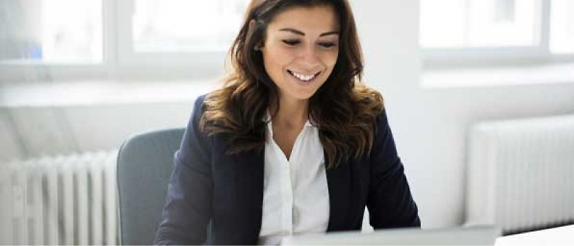 En kvinna som ler och sitter på ett kontor