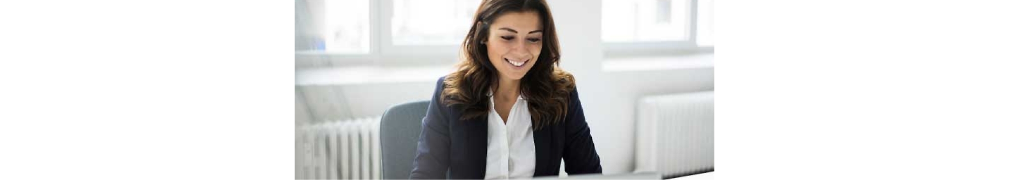 Femme dans un costume d’entreprise assis à un bureau avec un ordinateur portable.