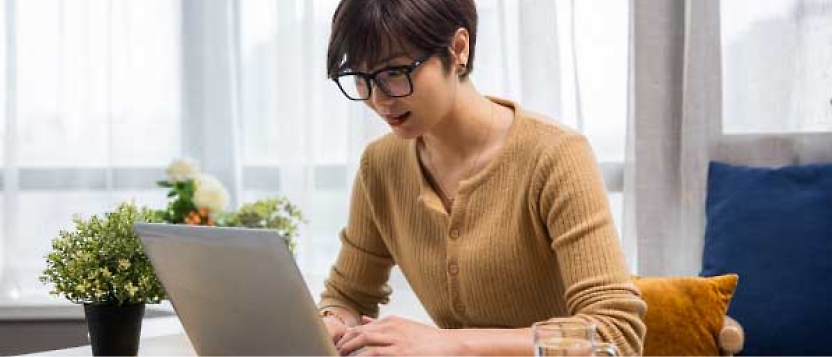 صورة امرأة تعمل على جهاز كمبيوتر محمول في المنزل.