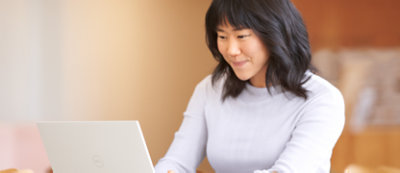 A woman is smiling and working on her laptop