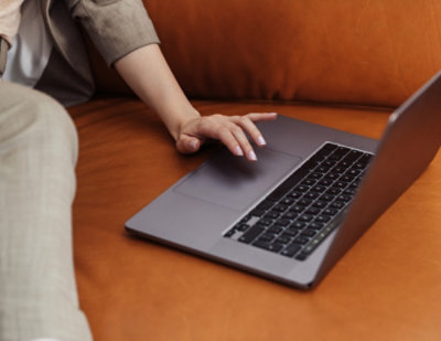 A person sitting down with their hand on a laptop.