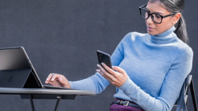  person seated using laptop while checking smartphone