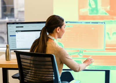 Person sitting at desk working in front of computer monitors
