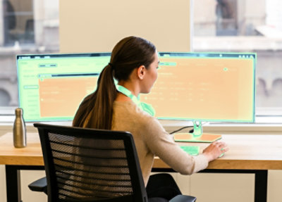 Person working at a desk with dual monitors.