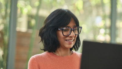 Woman using laptop with greenery behind her